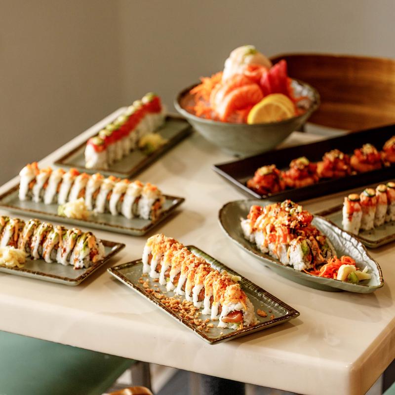 Assortment of sushi rolls served on the table alongside a sashimi platter.
