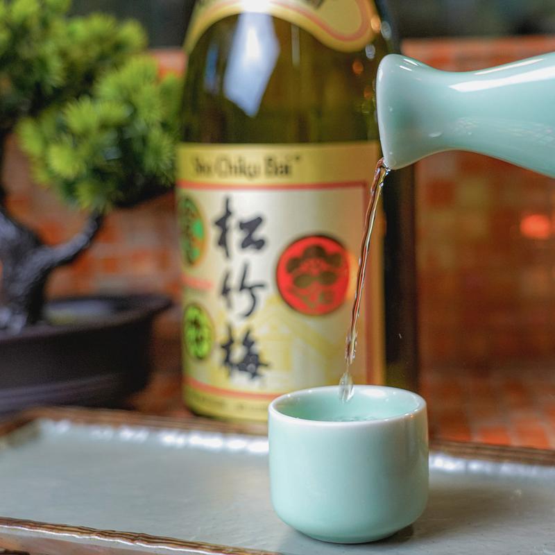 Sake being poured from a white carafe into a white cup.